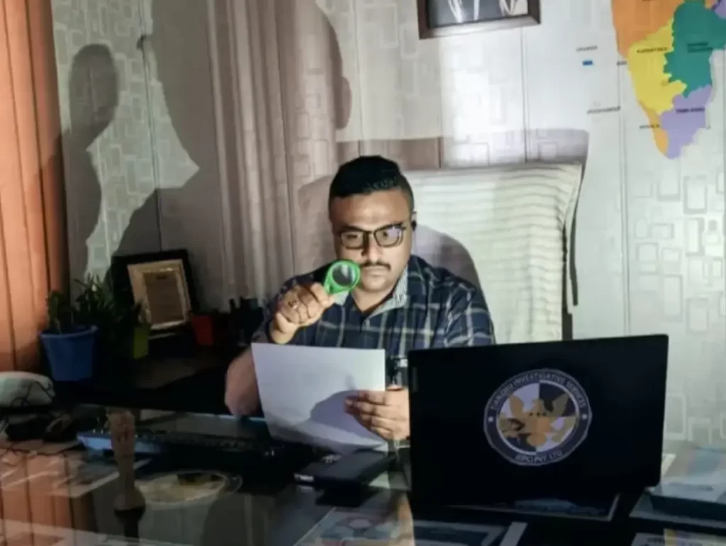 Detective working with searching glass at office desk.
